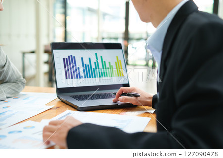 Two business people discuss financial strategy and collaborate with colleagues. Two business people discuss financial strategy and collaborate with colleagues. 127090478