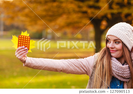 Woman in autumn park holding vitamins medicines 127090513