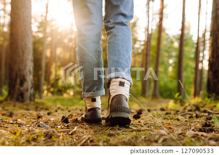 Feet of an adult wearing boots to travel walking in the forest. Feet walking in outdoor nature Feet of an adult wearing boots to travel walking in the forest. Feet walking in outdoor nature 127090533