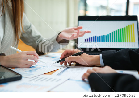 Two business people discuss financial strategy and collaborate with colleagues. 127090555