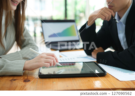 Two business people discuss financial strategy and collaborate with colleagues. Two business people discuss financial strategy and collaborate with colleagues. 127090562