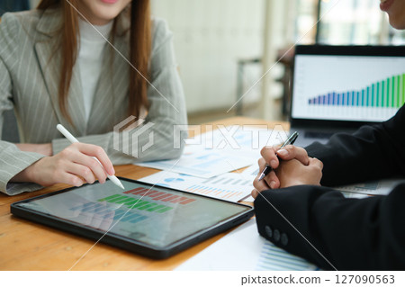 Two business people discuss financial strategy and collaborate with colleagues. Two business people discuss financial strategy and collaborate with colleagues. 127090563