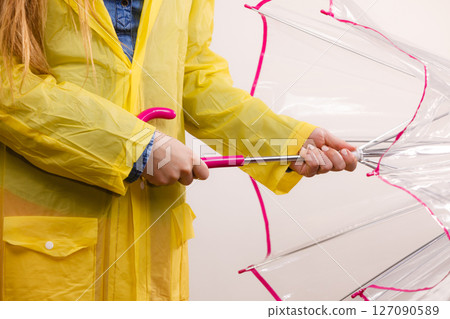 Woman wearing waterproof coat opening umbrella 127090589