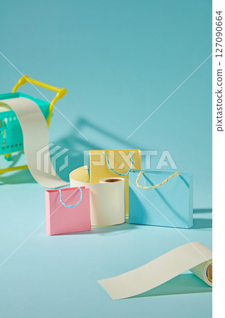 Cute paper cut shopping bags with mini bill rolls on blue background express the rush of online shopping and limited-time deals. Creative photography with shopping concept Cute paper cut shopping bags with mini bill rolls on blue background express the rush of online shopping and limited-time deals. Creative photography with shopping concept 127090664