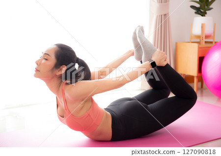 Young asian woman practicing Yoga with stretching muscle back on yoga mat in living room. 127090818