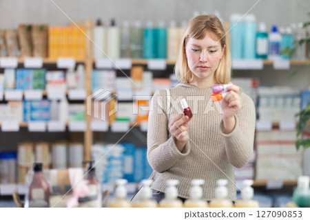 Woman choosing nail polishes in pharmacy 127090853