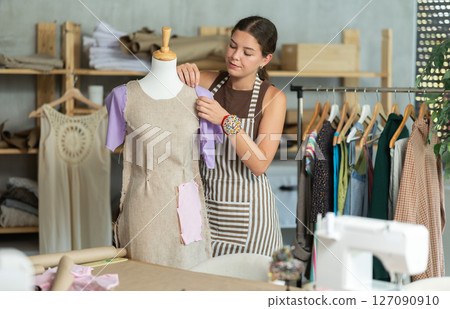 Female fashion designer working with mannequin and sewing fabric 127090910