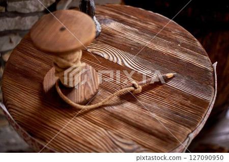Wedding decoration in the Slavic style. A wooden reel with a strong rope and a pencil. An element of the table for notes Wedding decoration in the Slavic style. A wooden reel with a strong rope and a pencil. An element of the table for notes 127090950