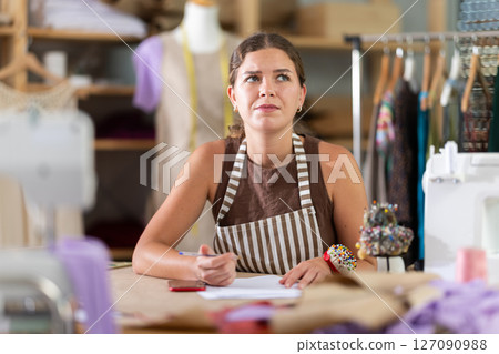 Upset woman with documents sitting at table Upset woman with documents sitting at table 127090988