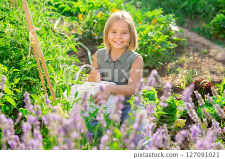 Portrait of little happy girl with basket on field with lavender 127091021