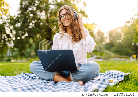 Young woman headphones sits listen to music use mobile cell phone. Concept for business, freelance. 127091101