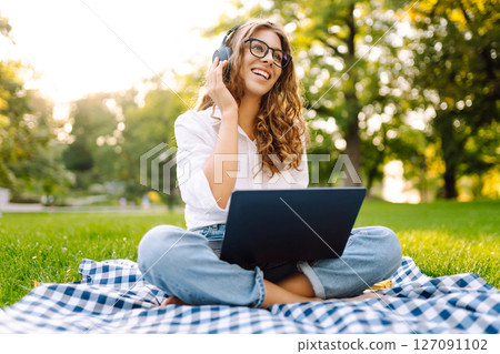 Young woman headphones sits listen to music use mobile cell phone. Concept for business, freelance. 127091102