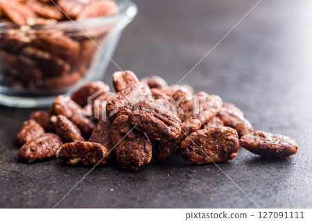 Pecan nuts coated in sugar and honey on black table. Pecan nuts coated in sugar and honey on black table. 127091111