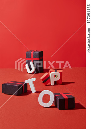 A playful paper cutout featuring a red gift box, curling ribbon, and the word UP TO on a vibrant red background. Festive layouts for peak sales events or holiday campaigns 127091188