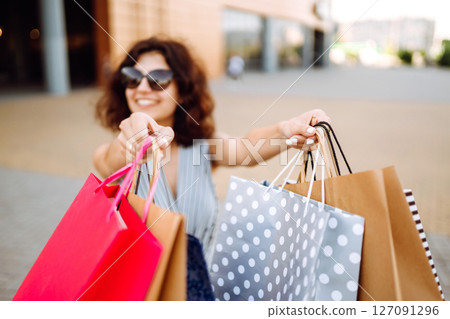 Shopping time. Young woman with shopping bags near the mall. Consumerism, sale, purchases. Shopping time. Young woman with shopping bags near the mall. Consumerism, sale, purchases. 127091296