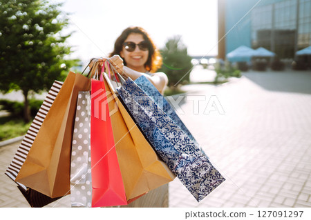 Shopping time. Young woman with shopping bags near the mall. Consumerism, sale, purchases. Shopping time. Young woman with shopping bags near the mall. Consumerism, sale, purchases. 127091297
