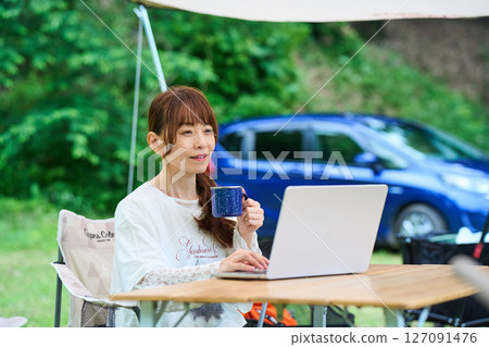 Outdoor barbecue camping senior woman computer 127091476