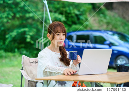 Outdoor barbecue camping senior woman computer 127091480