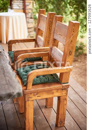 Wedding decoration in the Slavic style. Sturdy wooden thrones, chairs with green cushions 127091626