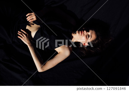 Slim brunette woman in black lingerie lying in bedroom on bed 127091846