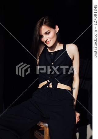 fashionable woman in black clothes sitting on chair in room fashionable woman in black clothes sitting on chair in room 127091849