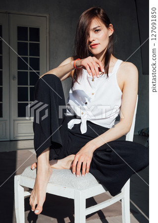fashionable woman in black clothes sitting on chair in room fashionable woman in black clothes sitting on chair in room 127091850