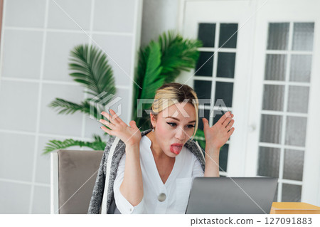 woman sitting at office desk with laptop and sticking out her tongue 127091883