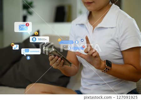 Close up of woman using a smartphone with floating social icons and notifications 127091925