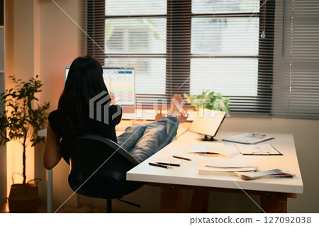 Relaxed graphic designer working from home, analyzing color charts on a computer screen Relaxed graphic designer working from home, analyzing color charts on a computer screen 127092038