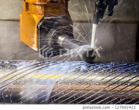 Metal cutting process in a workshop with water coolant spraying on a rotating shaft 127092422