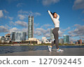 Sporty Woman Stretching Outdoors by the City Waterfront at Sunrise 127092445