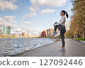 Sporty Woman Stretching Outdoors by the City Waterfront at Sunrise 127092446