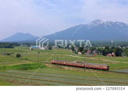 The Tokitetsu sightseeing express train runs smoothly through rice fields where rice planting has already been completed, at the foot of Mt. Myoko where snow still remains. The Tokitetsu sightseeing express train runs smoothly through rice fields where rice planting has already been completed, at the foot of Mt. Myoko where snow still remains. 127093314