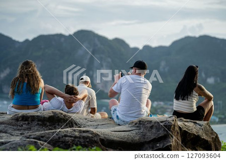 A group of guys are sitting on a rock and admiring the panorama of the island 127093604
