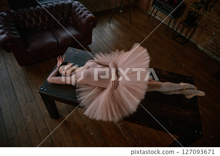 An elegant and graceful ballerina posed on a dark table surrounded by soft tutu fabric An elegant and graceful ballerina posed on a dark table surrounded by soft tutu fabric 127093671