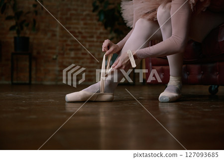 Ballerina is gently and delicately wearing her ballet shoes 127093685
