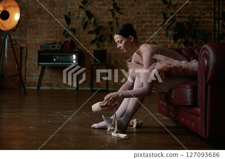 Ballerina is gently and delicately wearing her ballet shoes Ballerina is gently and delicately wearing her ballet shoes 127093686