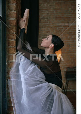 An elegant ballerina stretching gracefully in a beautiful and artistic studio setting 127093753