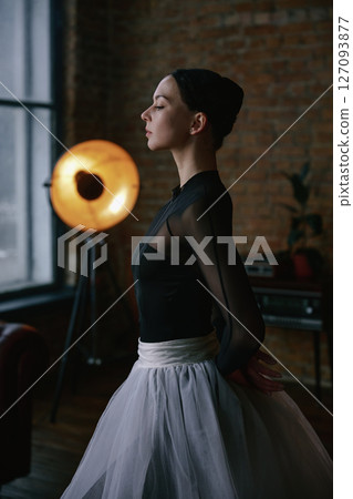 An elegant ballerina gracefully poised in a stunning modern studio setting illustrates artistry 127093877