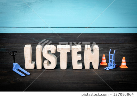 Listen. Concrete alphabet letters on a blue and black wooden background Listen. Concrete alphabet letters on a blue and black wooden background 127093964