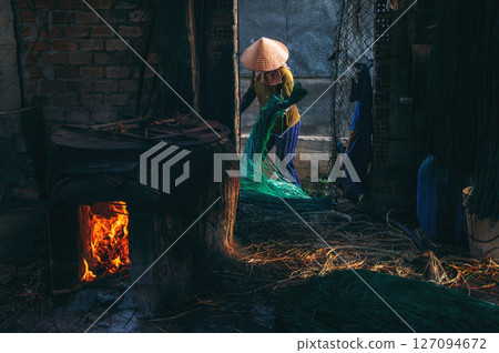 Vietnamese woman in a traditional straw hat works in a reed dyeing workshop for the production of woven mats in Vietnam 127094672