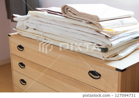 Kimono and obi piled up on top of a kimono chest 127094731