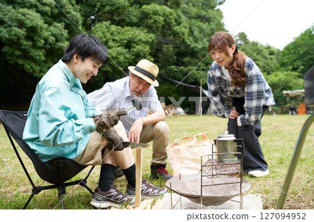 Young man splitting firewood with a hammer and knife Batoning image 127094952