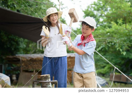 Elementary school boy trying to chop firewood 127094953