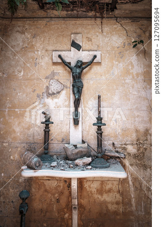 Old Crucifix on a Decayed Altar in an Abandoned Chapel 127095694