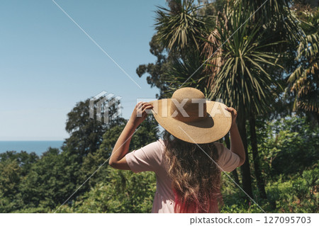 Woman with Straw Hat Looking at Lush Forest Woman with Straw Hat Looking at Lush Forest 127095703