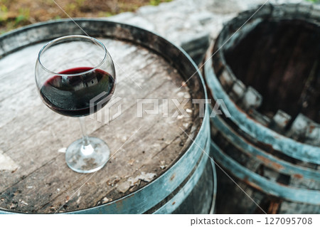 Glass of Red Wine on Old Oak Barrel in Rustic Cellar Glass of Red Wine on Old Oak Barrel in Rustic Cellar 127095708