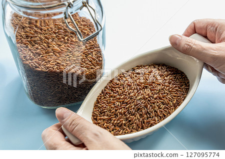 Female hands holding healthy uncooked raw red rice Female hands holding healthy uncooked raw red rice 127095774