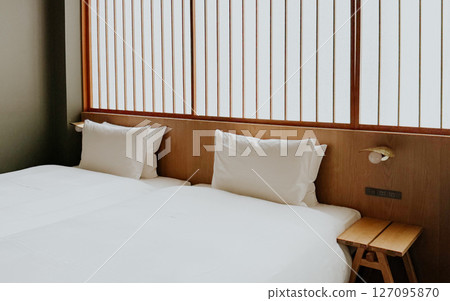 Minimalist Japanese hotel room with twin beds and soft white bedding, shoji screen. Modern ryokan interior  127095870