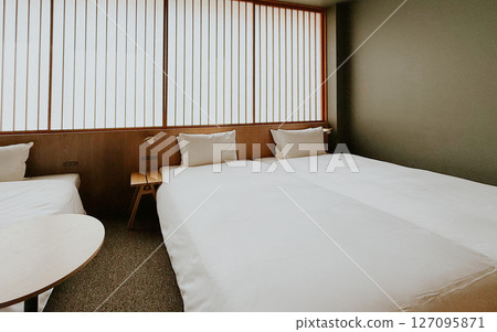 Minimalist Japanese hotel room with twin beds and soft white bedding, shoji screen. Modern ryokan interior  127095871